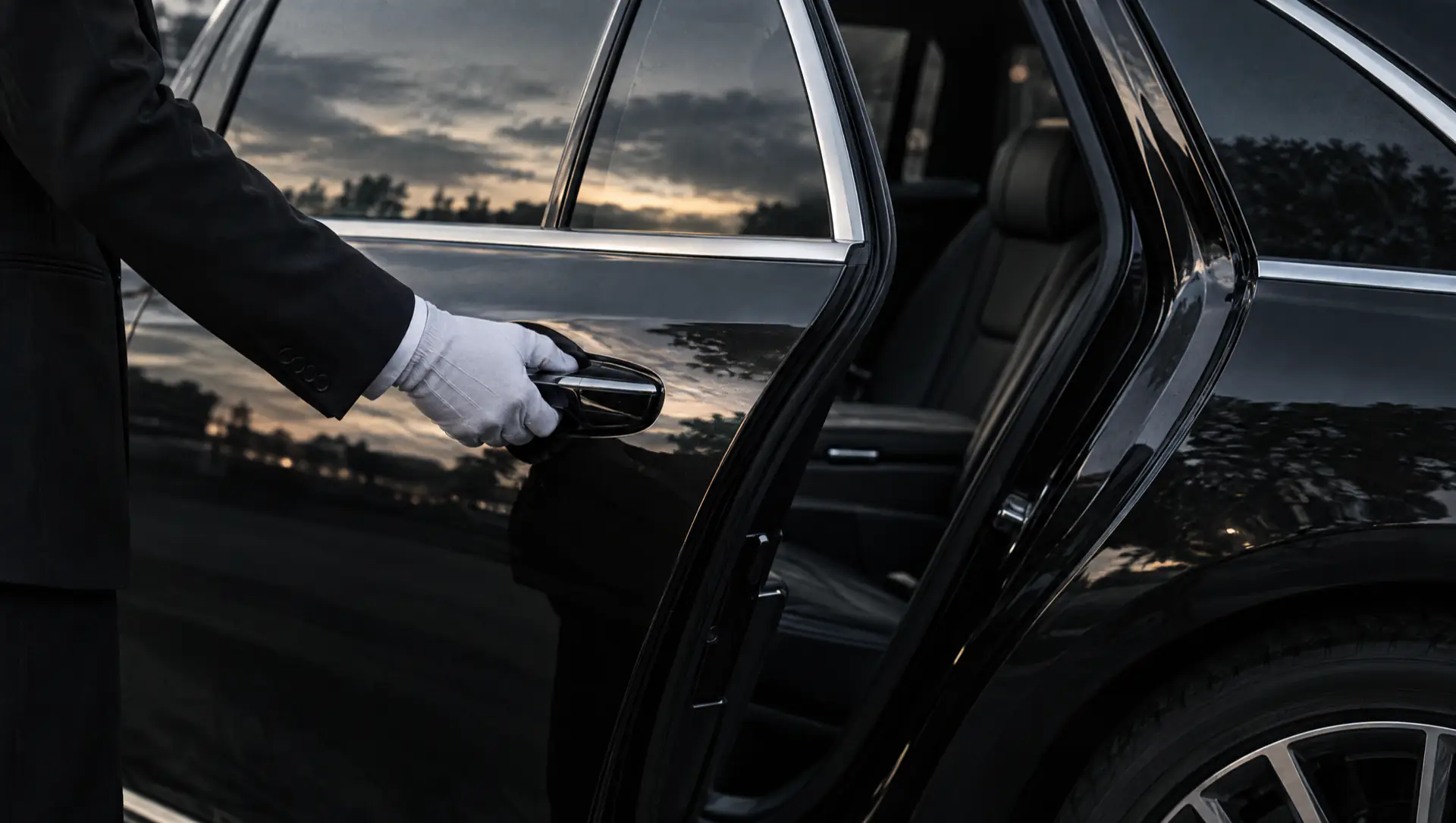 A chauffeur’s gloved hand on the door of a black saloon.